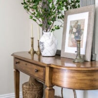 entry table decorated for spring with vase of branches and spring floral art