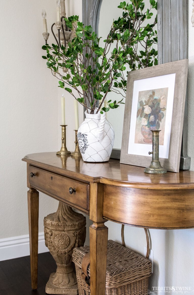 entry table decorated for spring with vase of branches and spring floral art