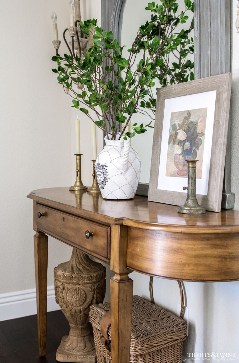 entry table decorated for spring with vase of branches and spring floral art