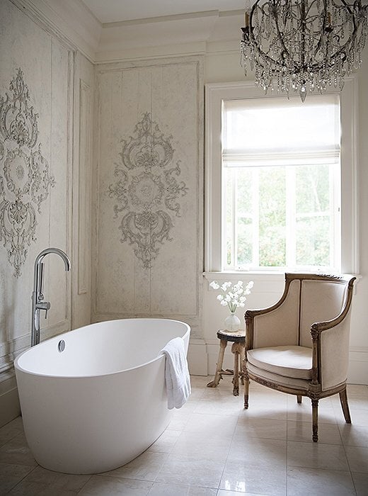 bathroom with freestanding tub and french chair next to it with antique panels on the walls