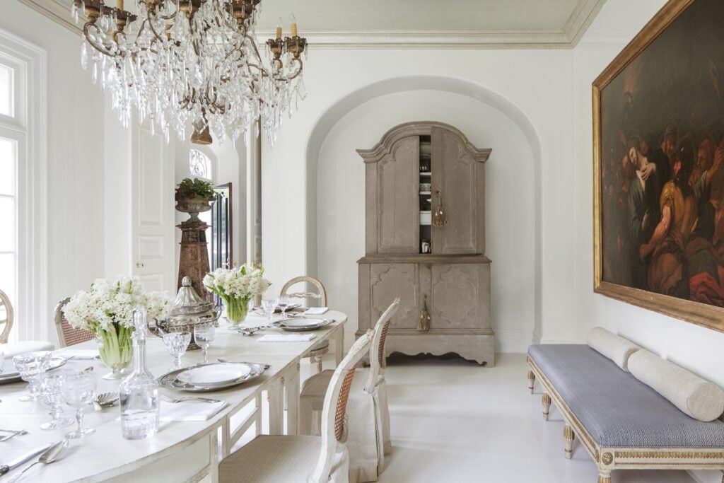 dining room with french table and chairs and large crystal chandelier and painting of jesus