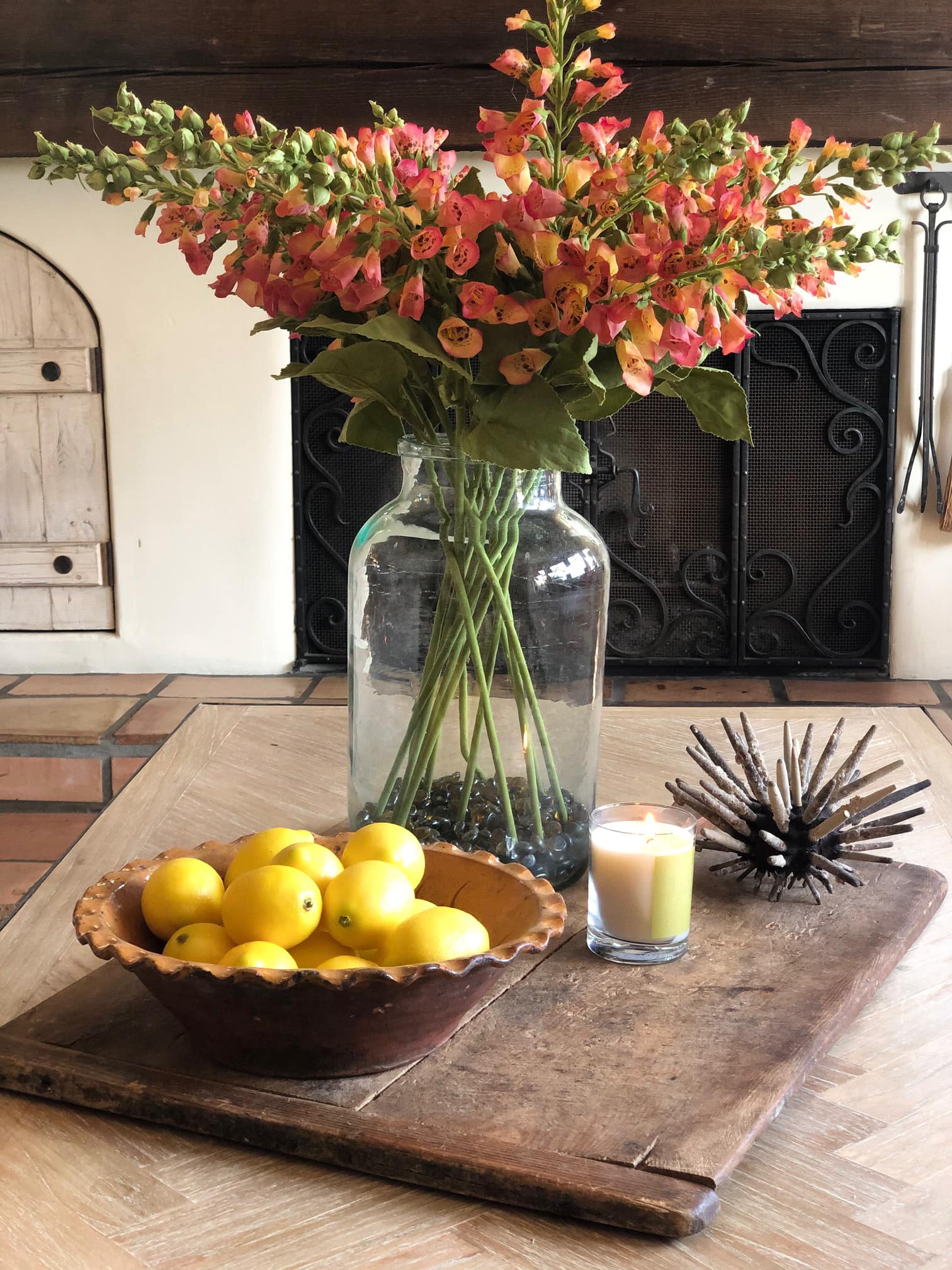 coffee table with large antique bread board holding flower stems and a bowl of lemons