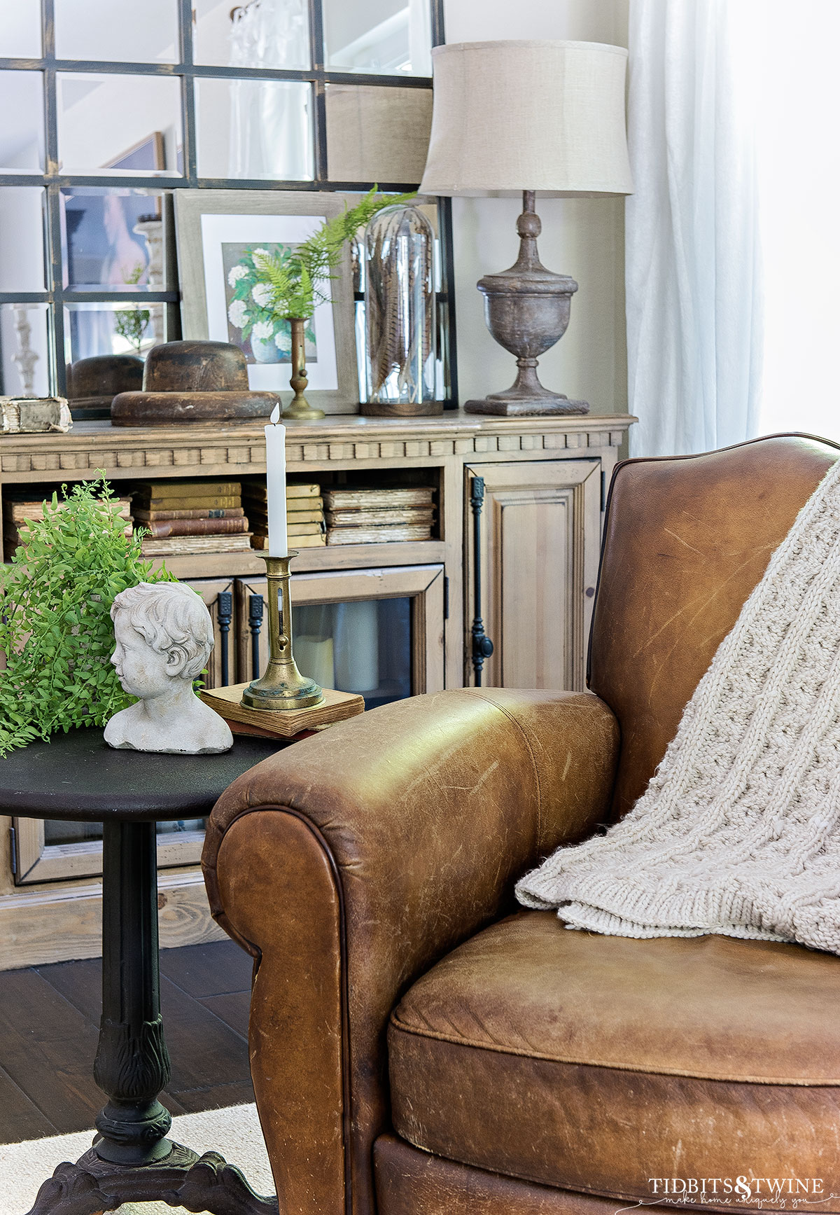 leather recliner chair next to bistro side table with candlestick and a plant and console table in background