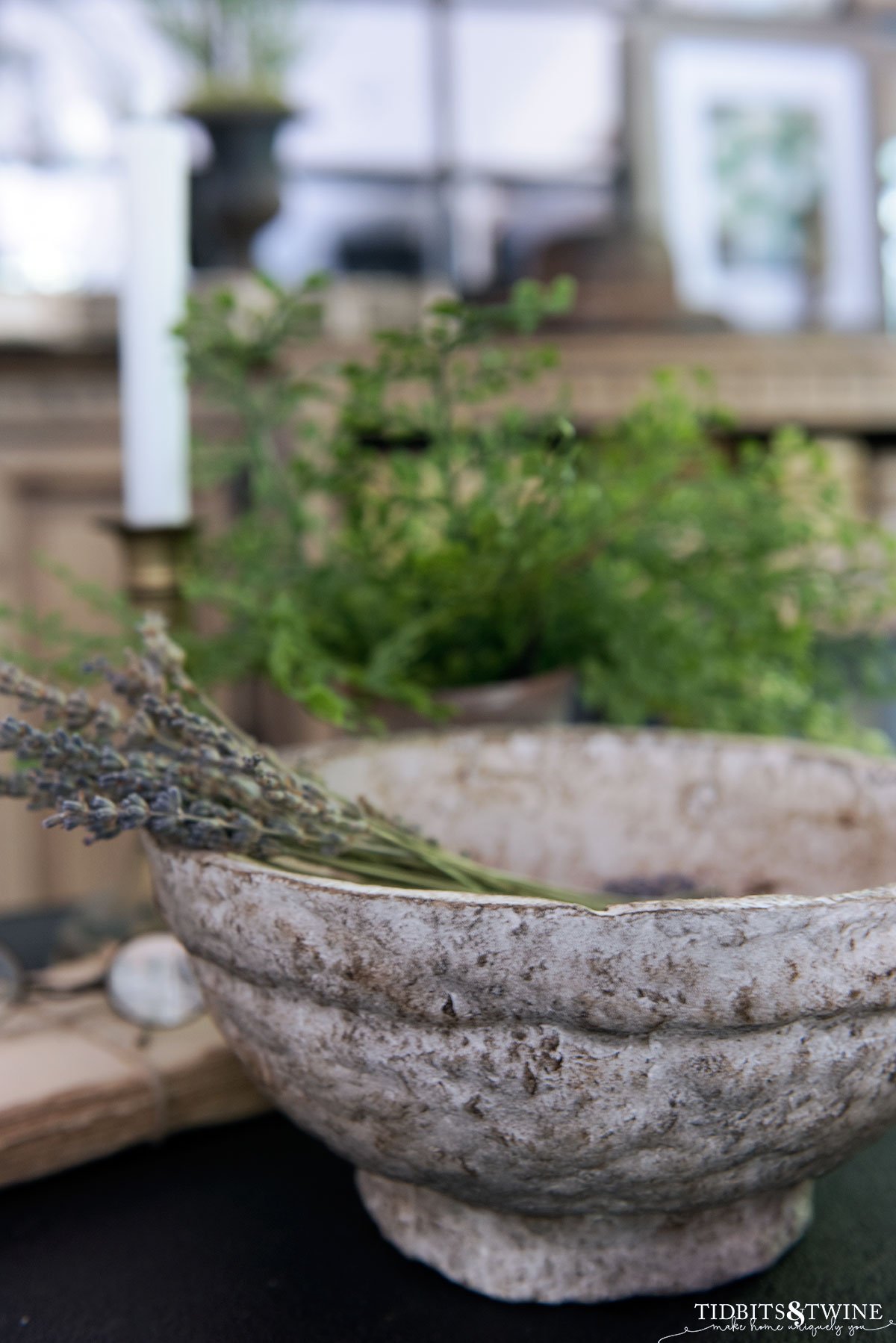 side table vignette with diy paper mache bowl holding lavender stems and green plant in the background