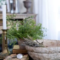 side table vignette with diy paper mache bowl holding lavender stems next to an old book with glasses