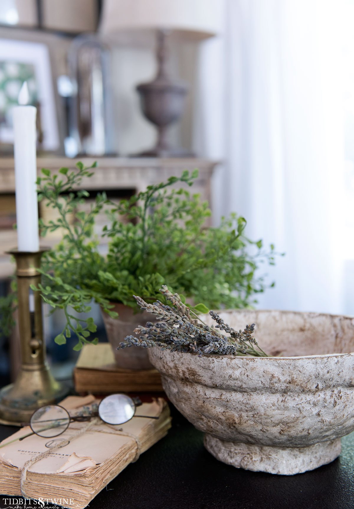 side table vignette with diy paper mache bowl holding lavender stems next to an old book with glasses