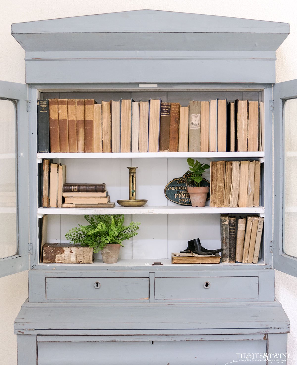 antique french blue cabinet styled with books and small plants for spring