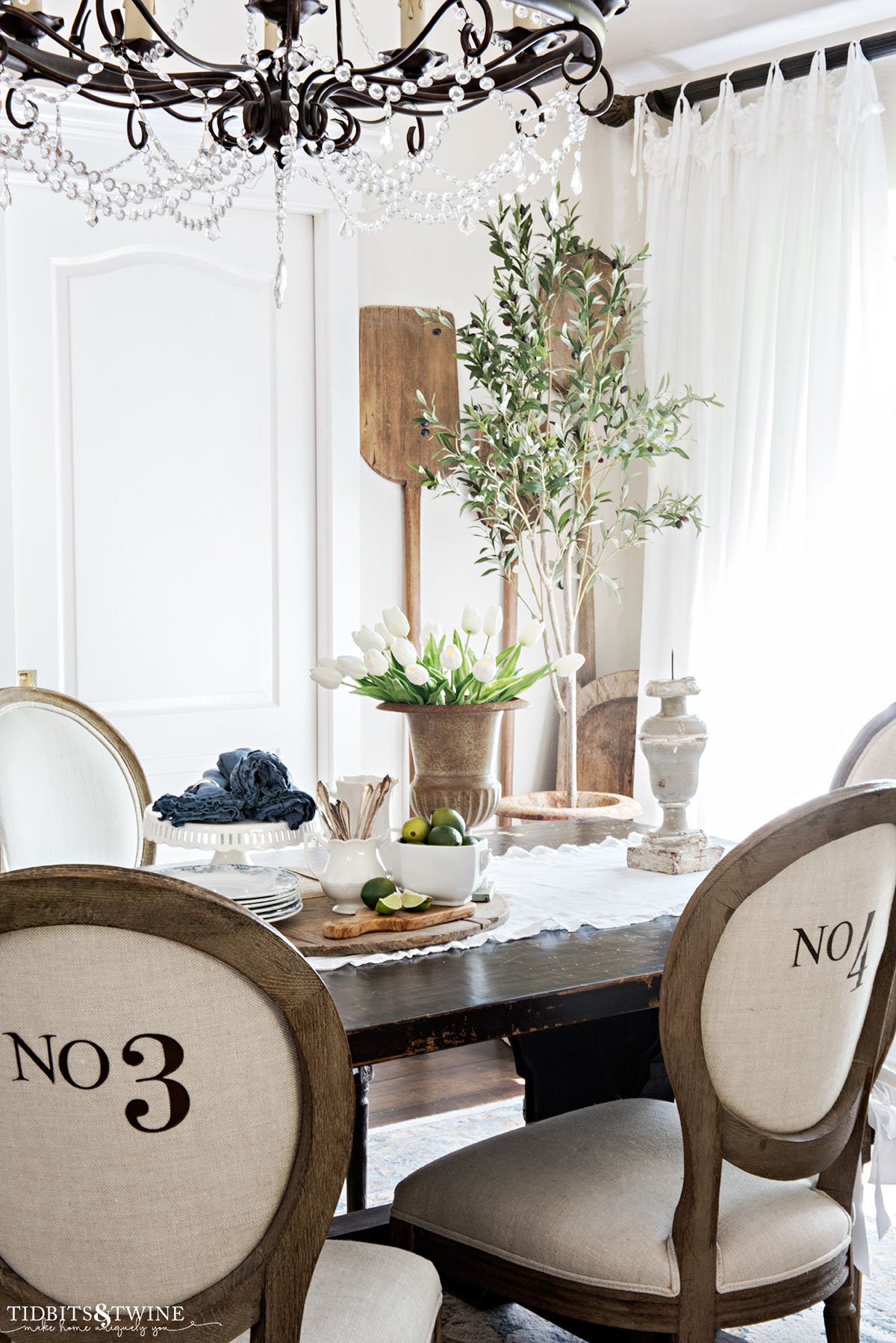 french dining room styled for spring with vignette in center of table with tulips and limes and dishes