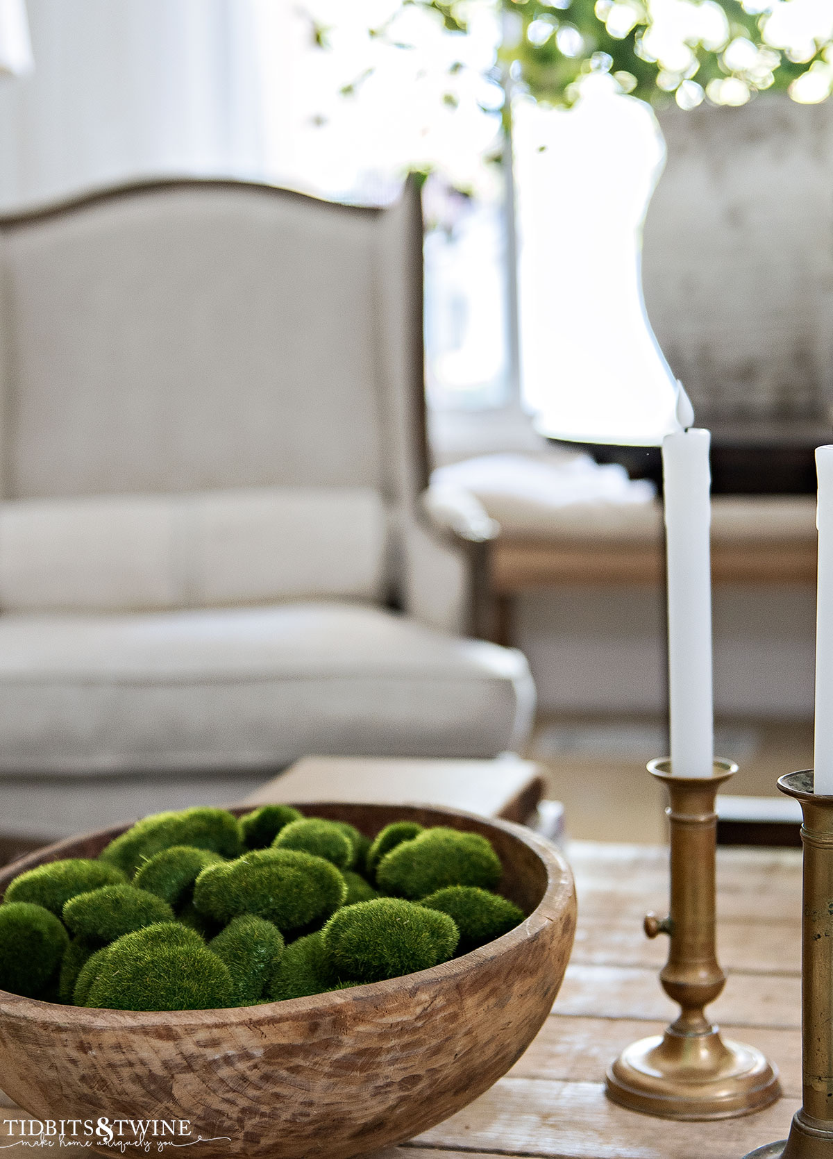 antique round dough bowl filled with faux moss rocks on coffee table next to french candlesticks