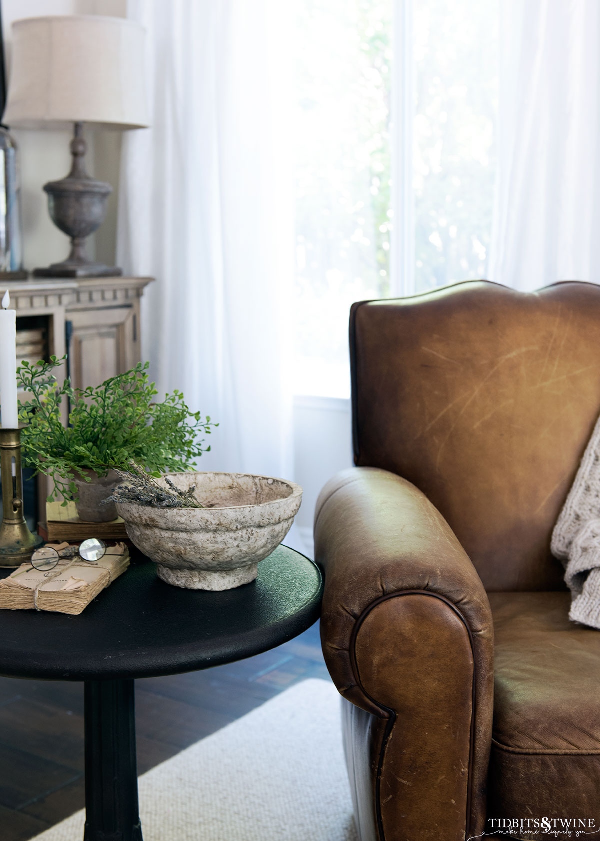 family room with leather chair and metal bistro table net to it with paper mache bowl vignette