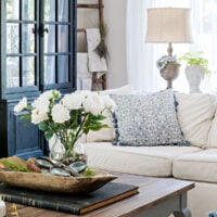spring family room with slipcovered sectional and french coffee table holding white flowers