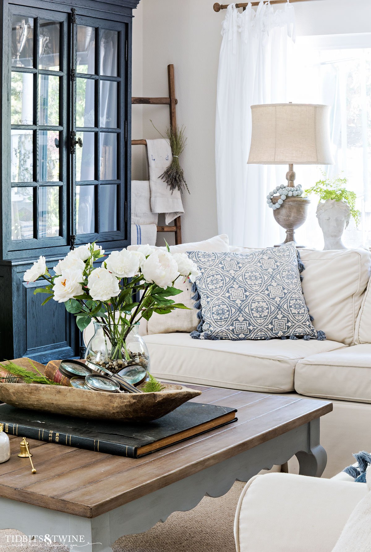 spring family room with slipcovered sectional and french coffee table holding white flowers