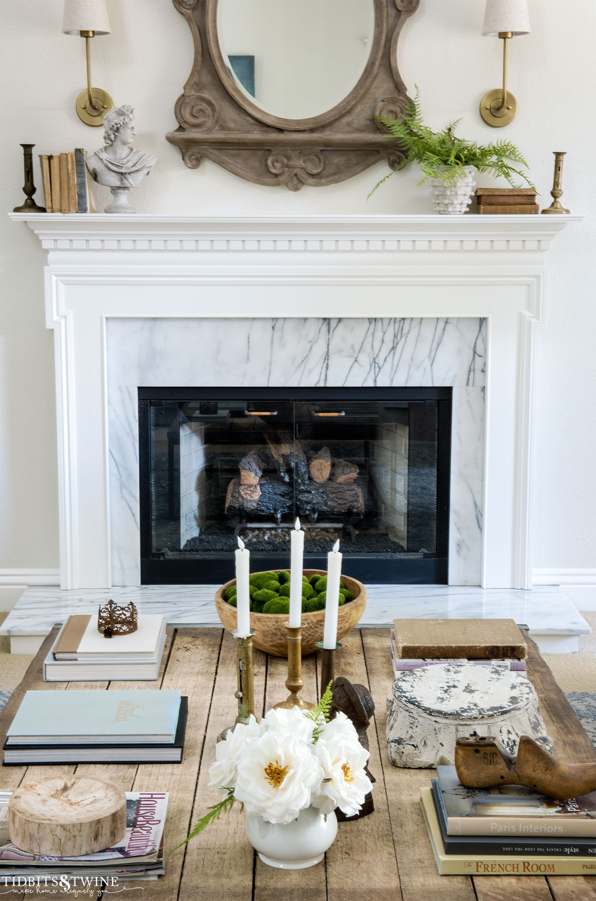 industrial coffee table with books candles and spring decor in front of white fireplace mantel 