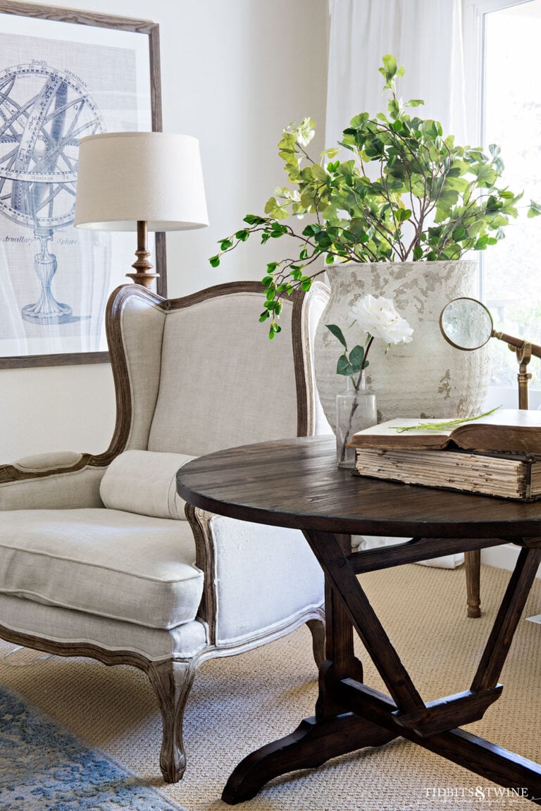 linen french wingback chair next to antique wine tasting table in spring living room