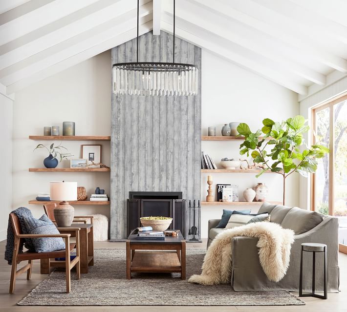 vaulted family room with large fireplace gray sofa and floating shelves