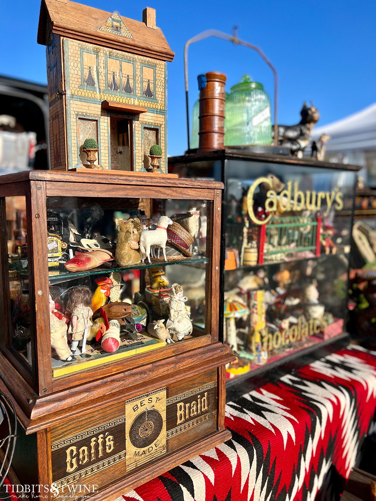 small wood and glass display cases filled with antique dolls and shoes