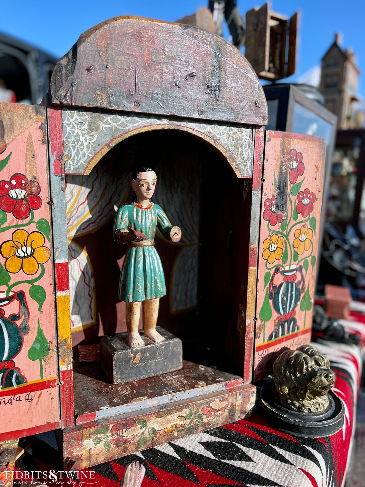 antique religious santos wearing green dress in a red and yellow flower box