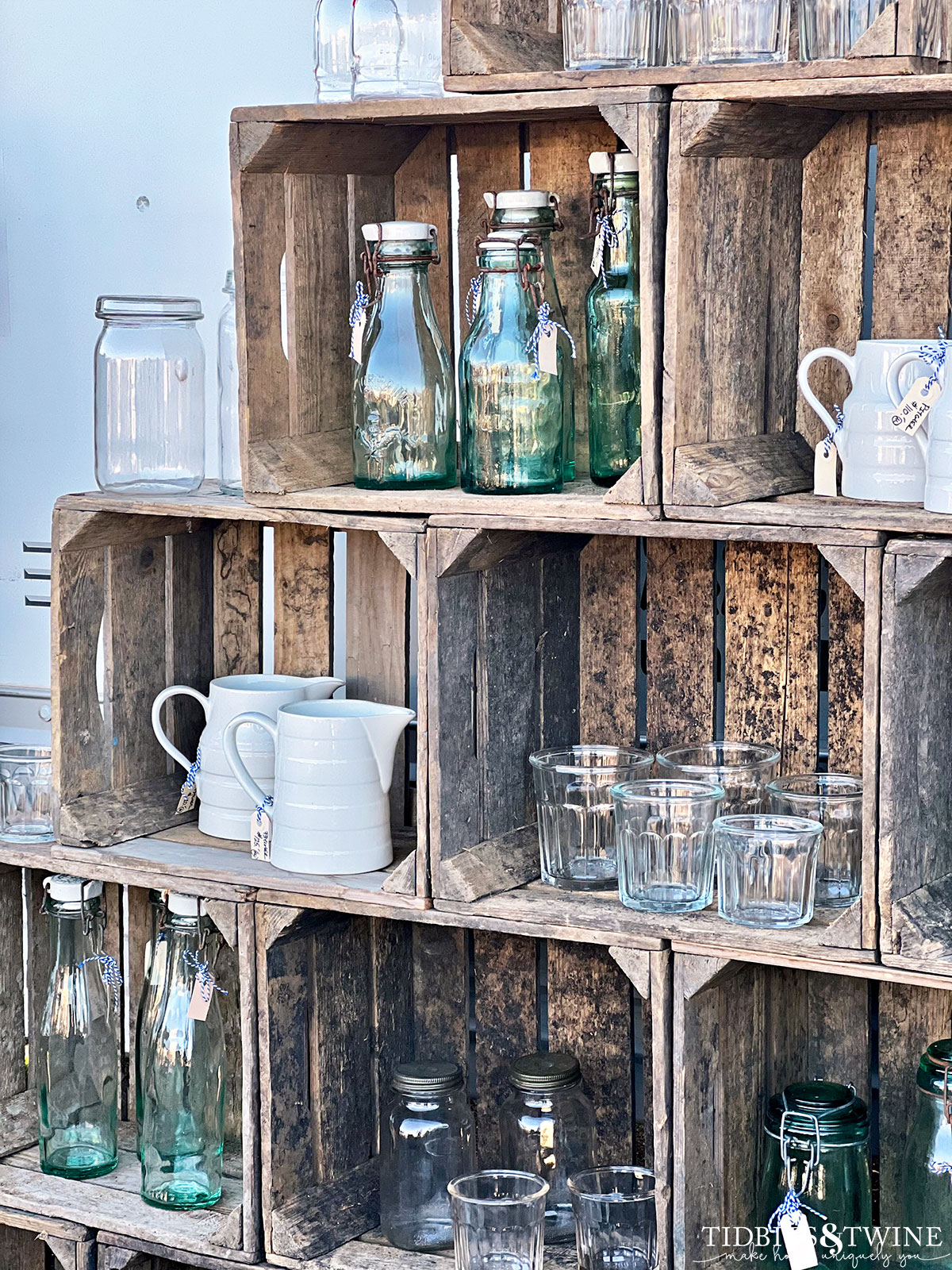 antique crate display with white ironstone pitchers and class milk bottles