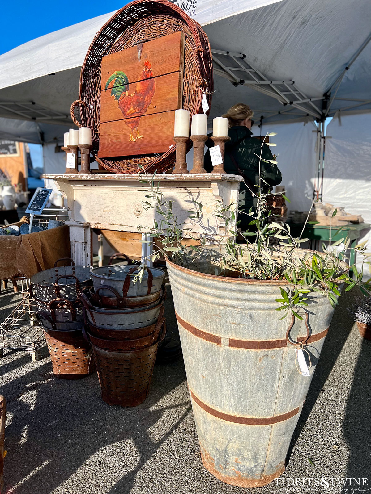 large galvanized bucket with olive branches in front of an antique carved mantel