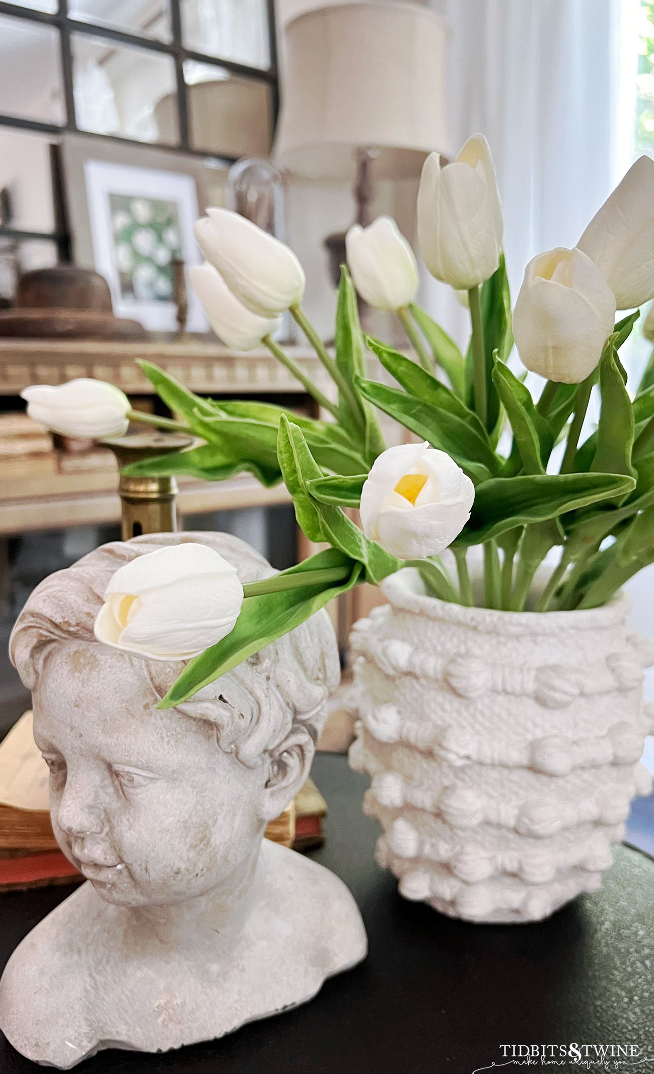 faux white tulips in rustic vase as part of side table vignette next to cherub statue head