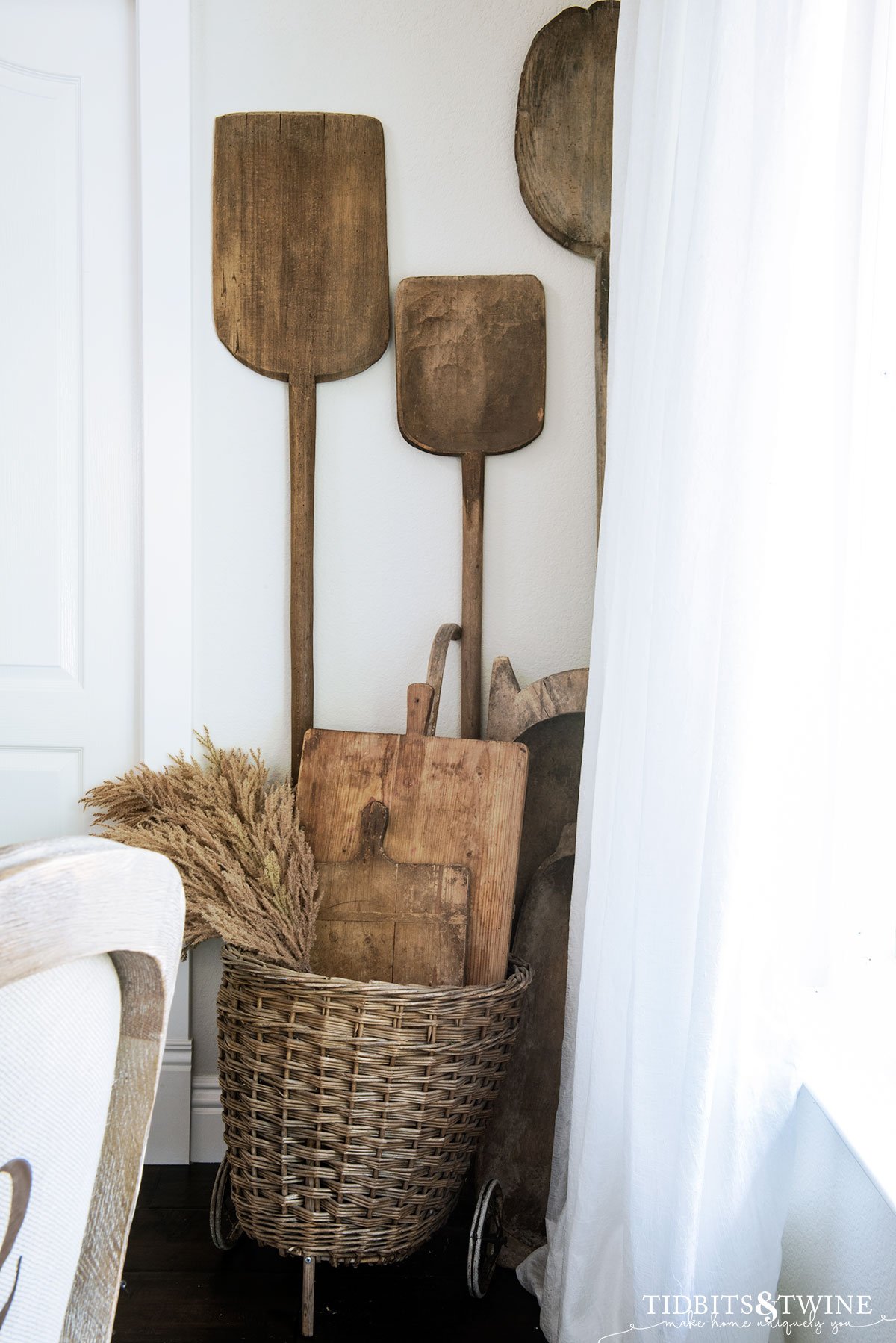 antique woven market basket holding antique bread boards in the corner of a dining room