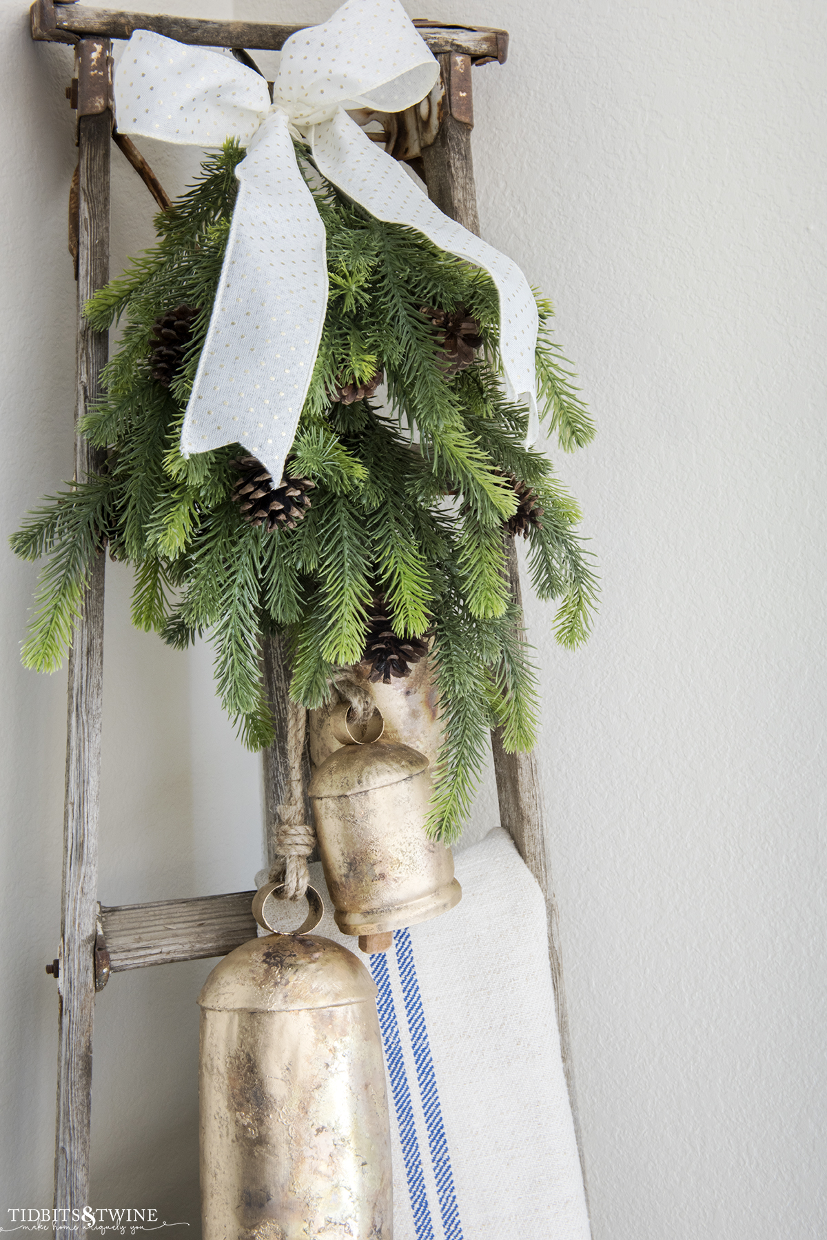 Orchard ladder decorated for Christmas with grain sacks, greenery, and bells