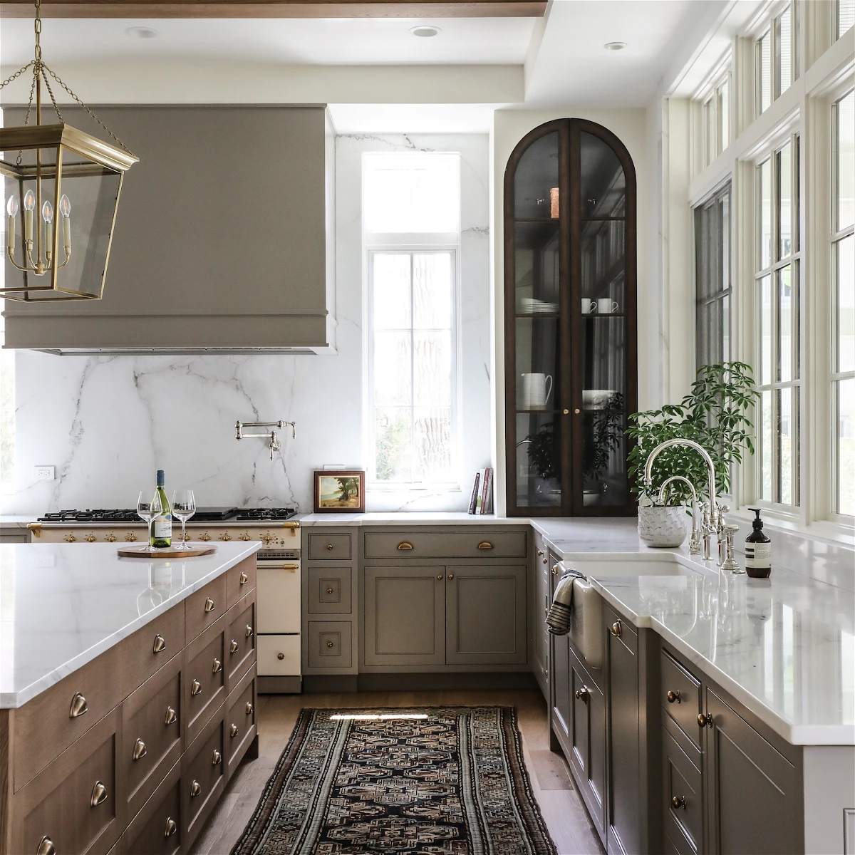 sage kitchen cabinets with wood island and black arched upper display cabinet