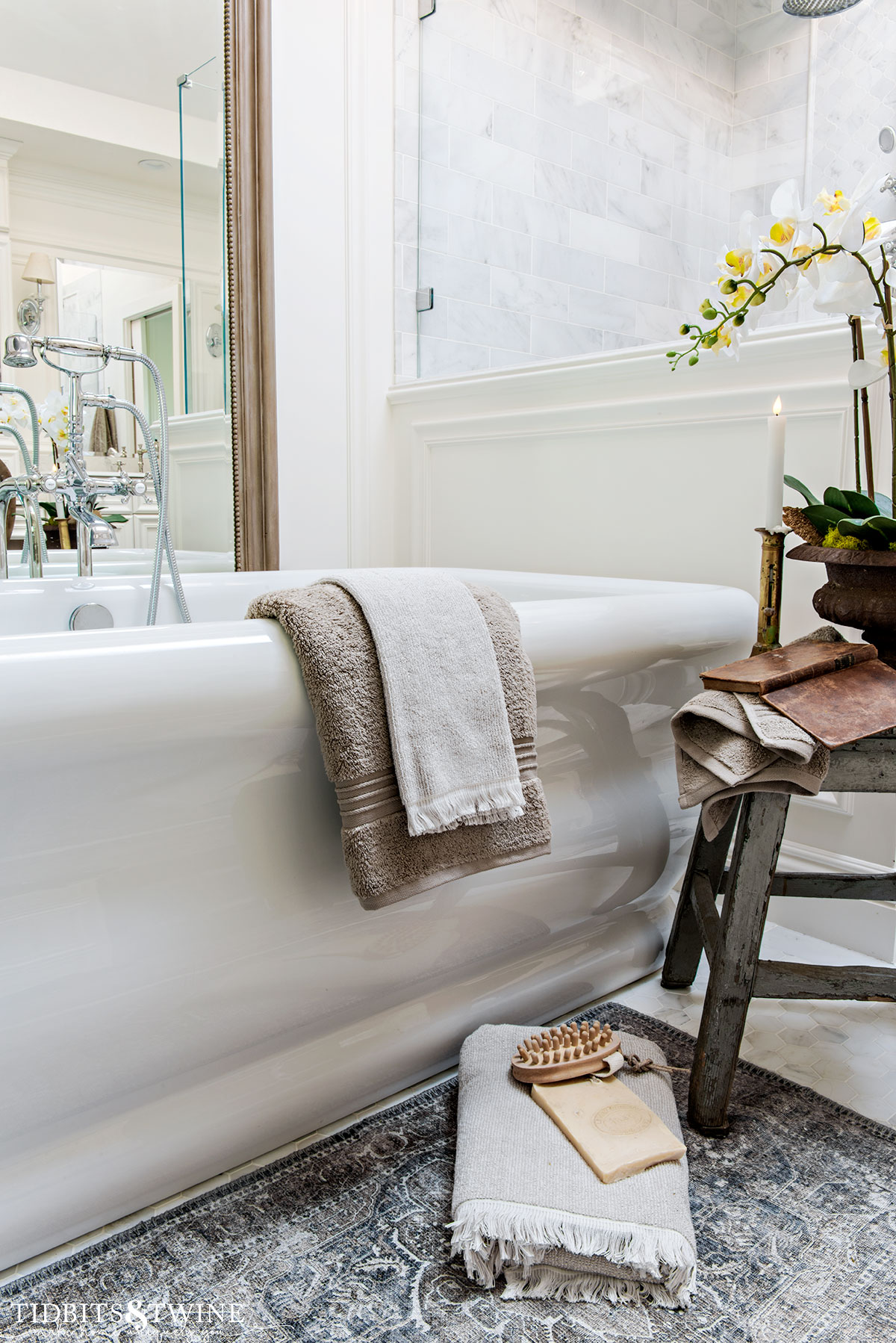 freestanding bathtub with towel draped over side and chippy stool with book