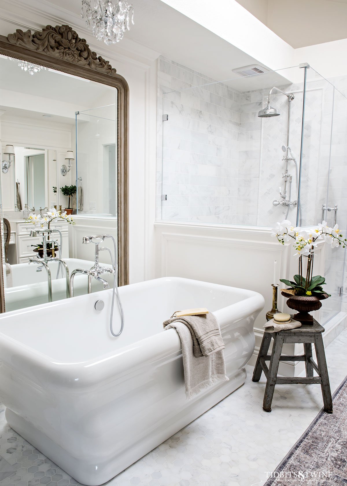 freestanding tub in carrara marble bathroom with large mirror behind tub