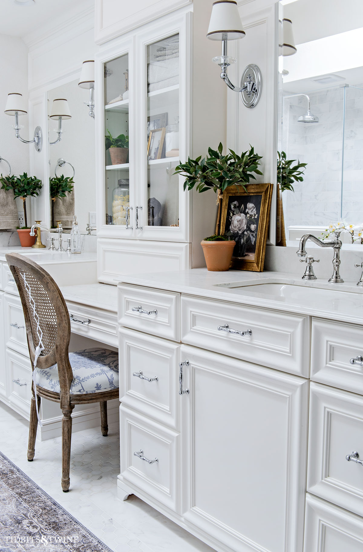 double white bathroom vanity with makeup area and shelving in the center and french side chair