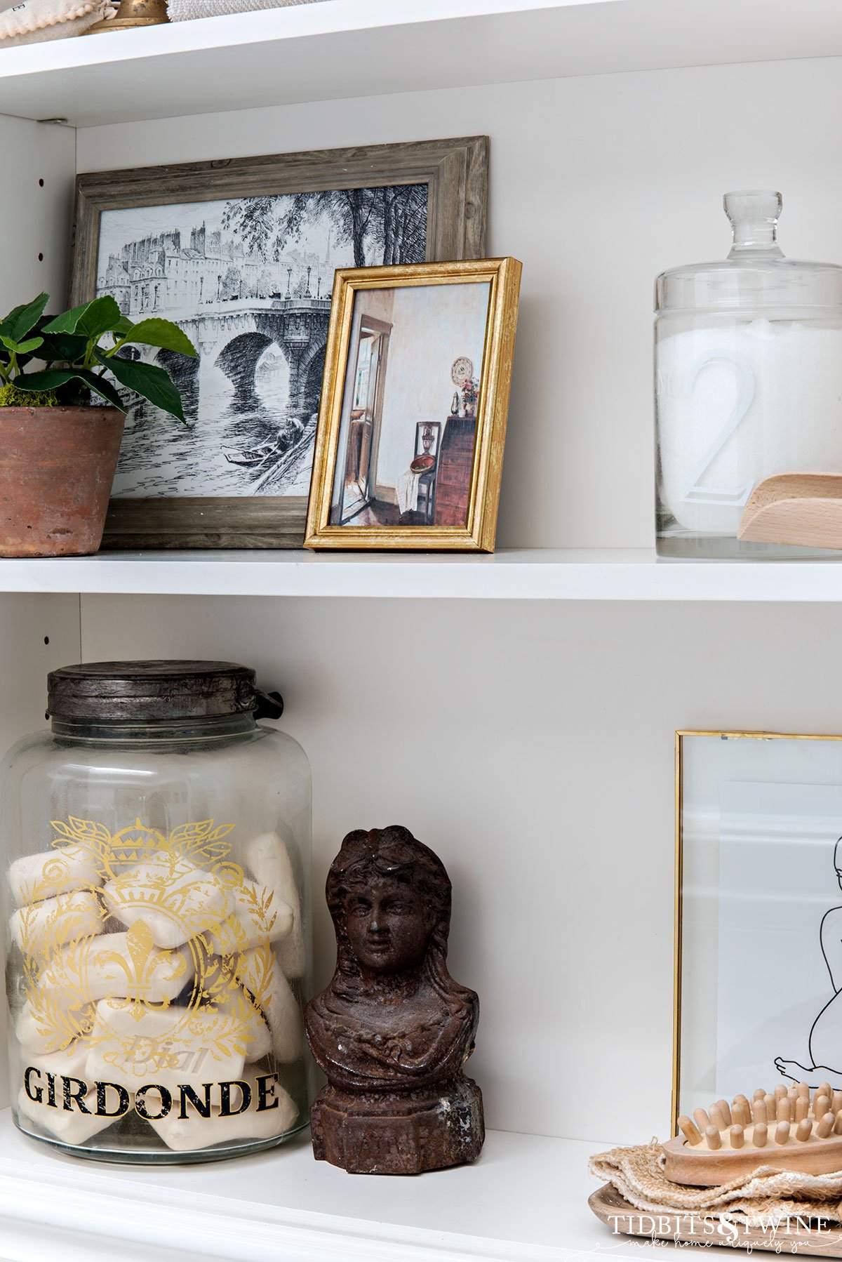 white bathroom cabinet styled with french art and vintage finds