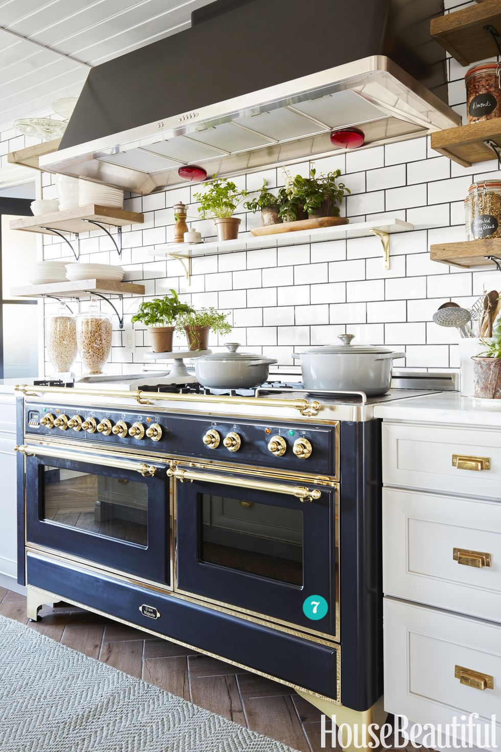 large brass and blue ilve range in kitchen with white cabinets and white subway tile