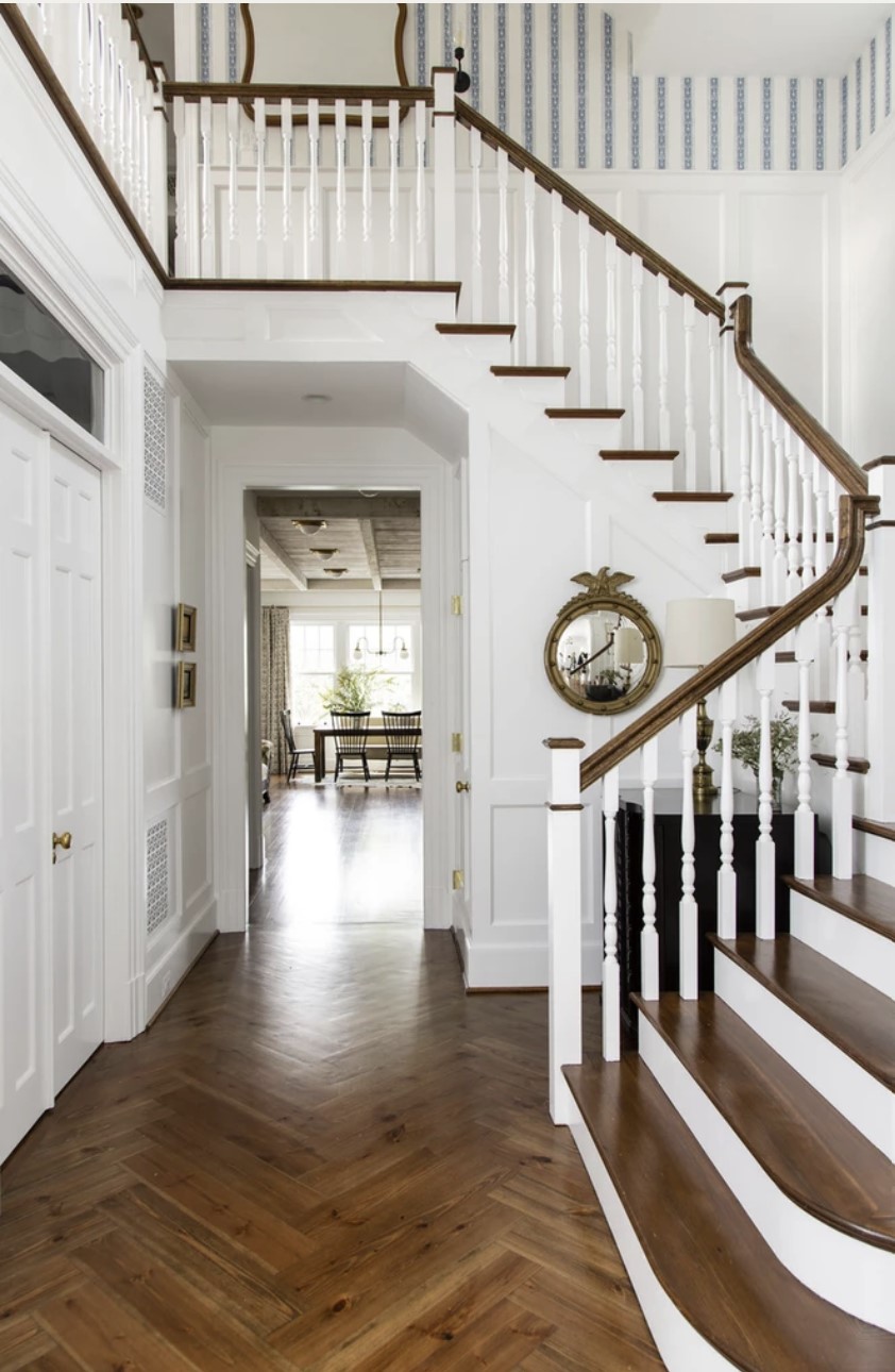 foyer with white moulding and hardwood floors and staircase with gold accents