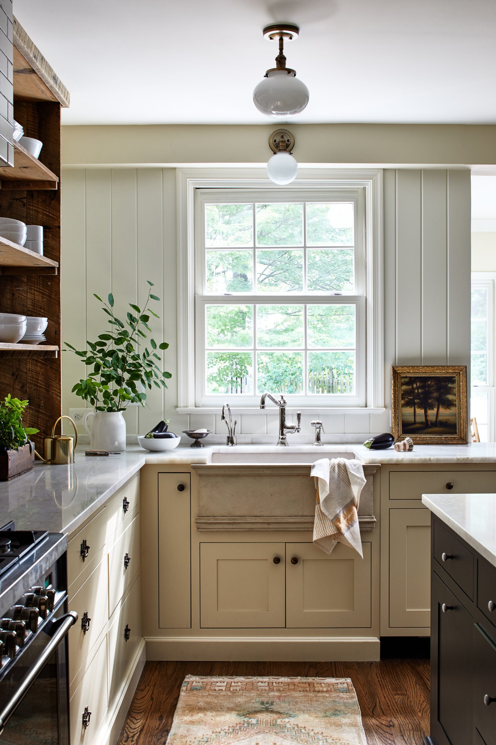 UKB kitchen with off white cabinets and black island and travertine farmhouse sink