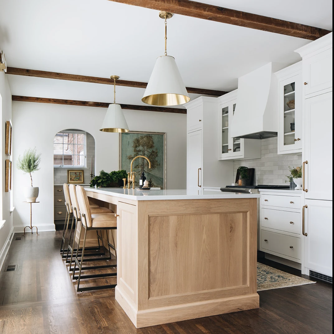 white kitchen cabinets with wood beams and wood island and brass hardware