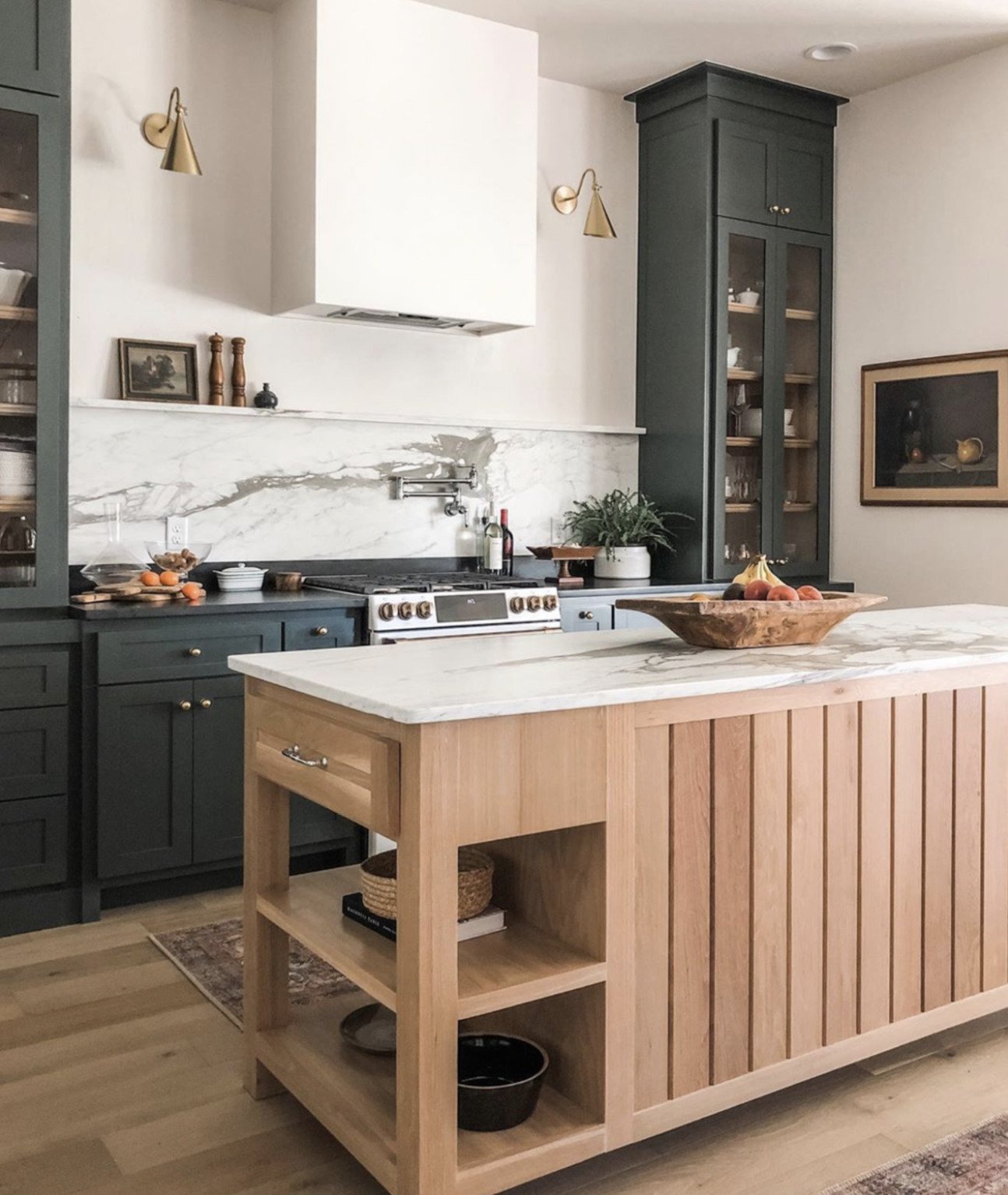 hunter green kitchen cabinets with marble backsplash and ledge and light wood island