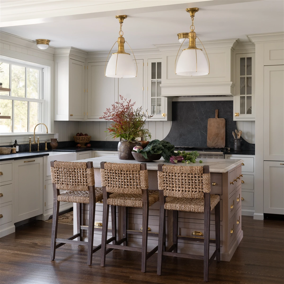 white kitchen with black countertop and backsplash and brass hardware