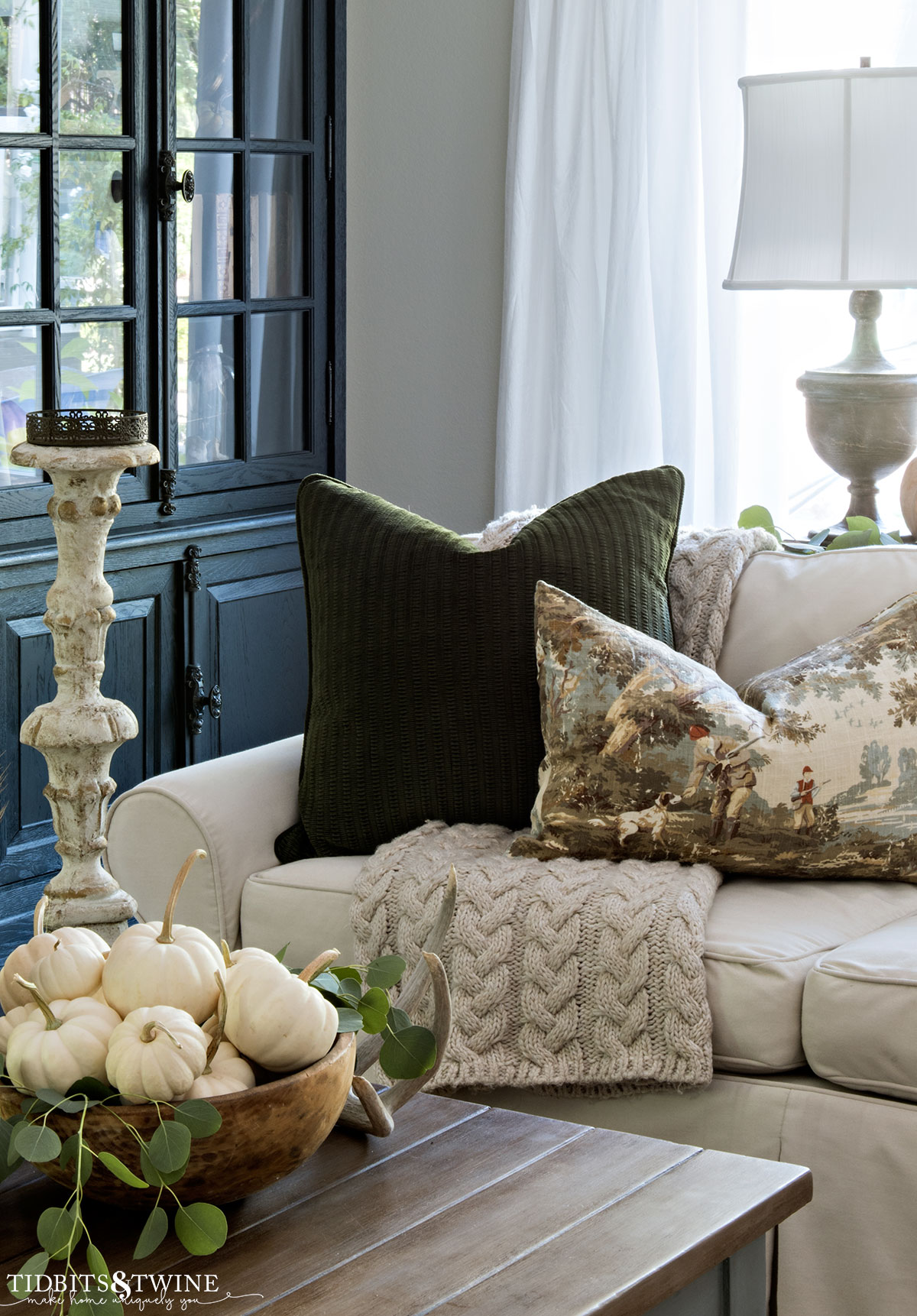 Fall family room with green throw pillow and bowl of white pumpkins on coffee table