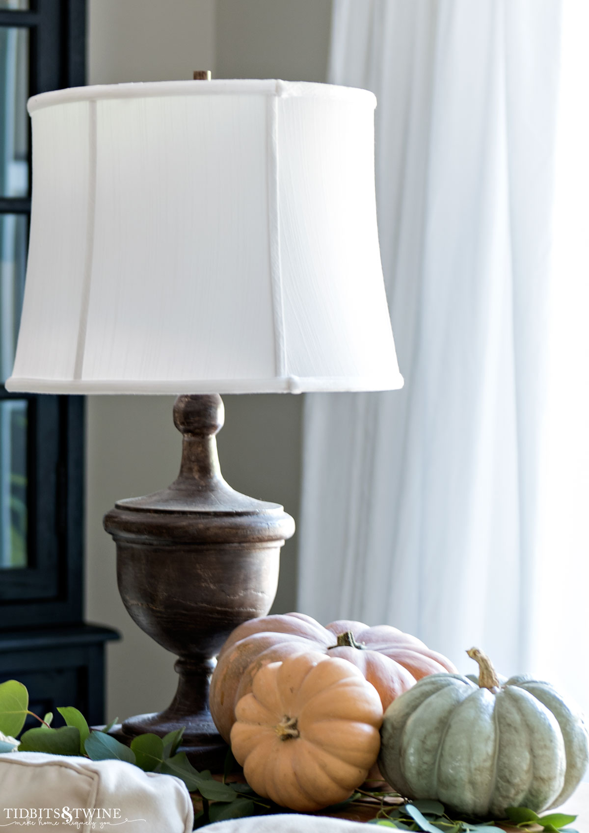 grouping of sage and terracotta pumpkins sitting on table next to a lamp for fall