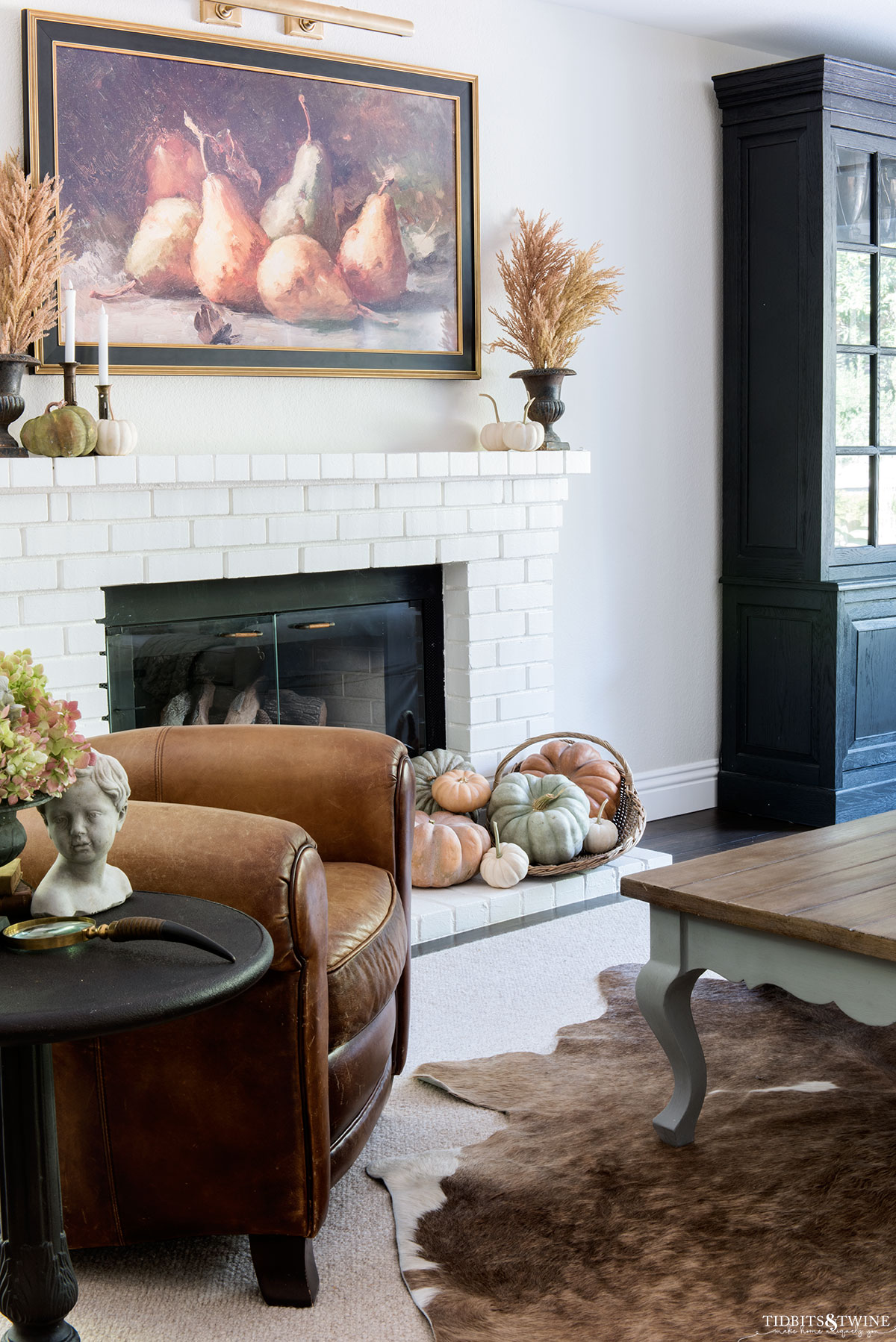 Fall family room with dried grasses on fireplace mantel and frame TV above with picture of pears