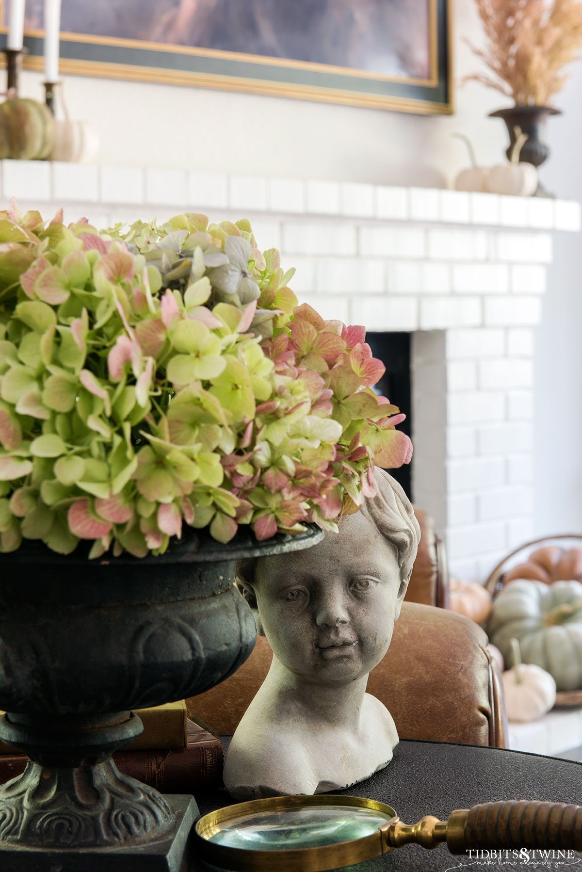 antique black cast iron urn holding hydrangeas with cherub statue at the base