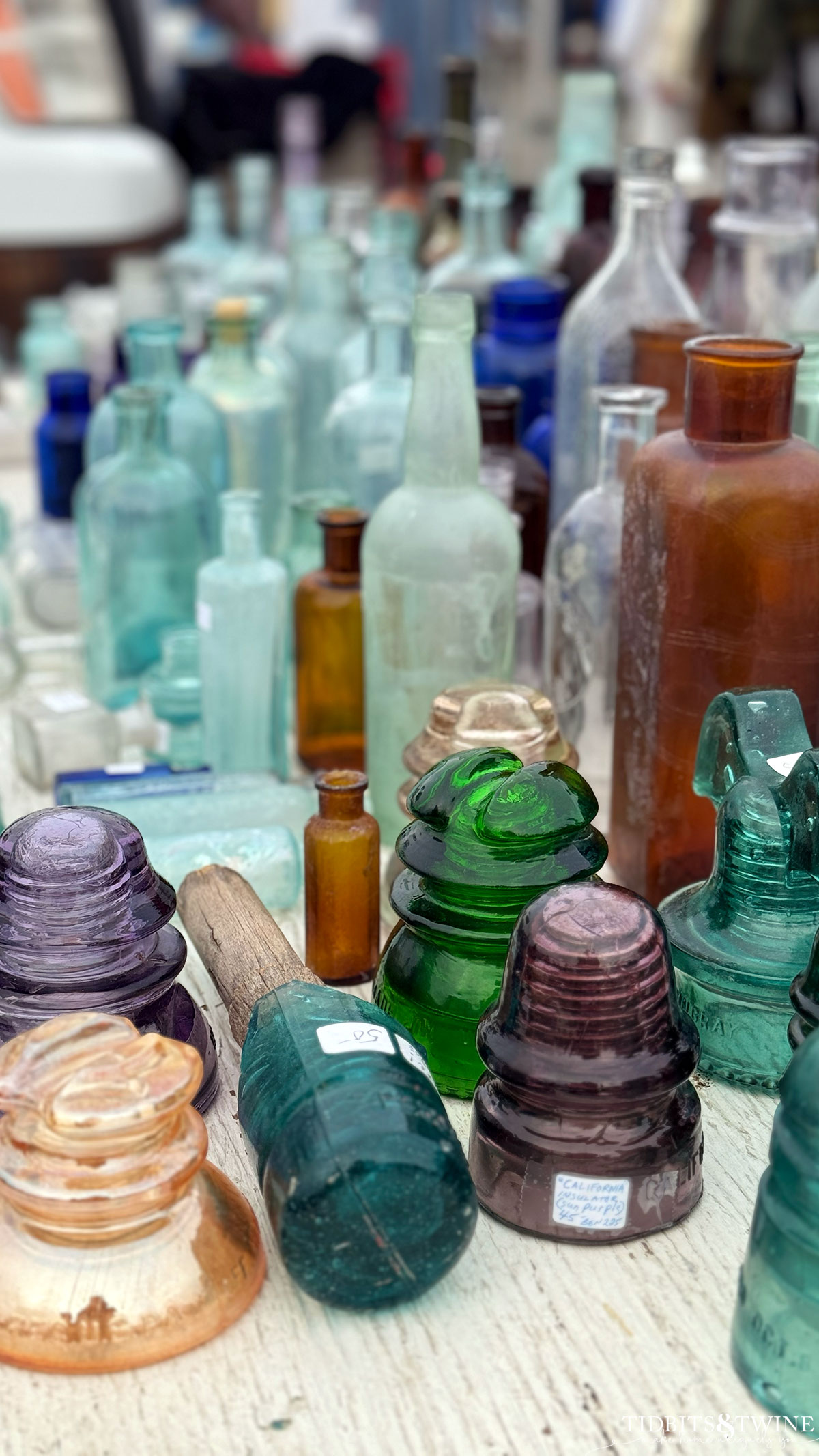 table display of antique bottles including green glass, blue and brown