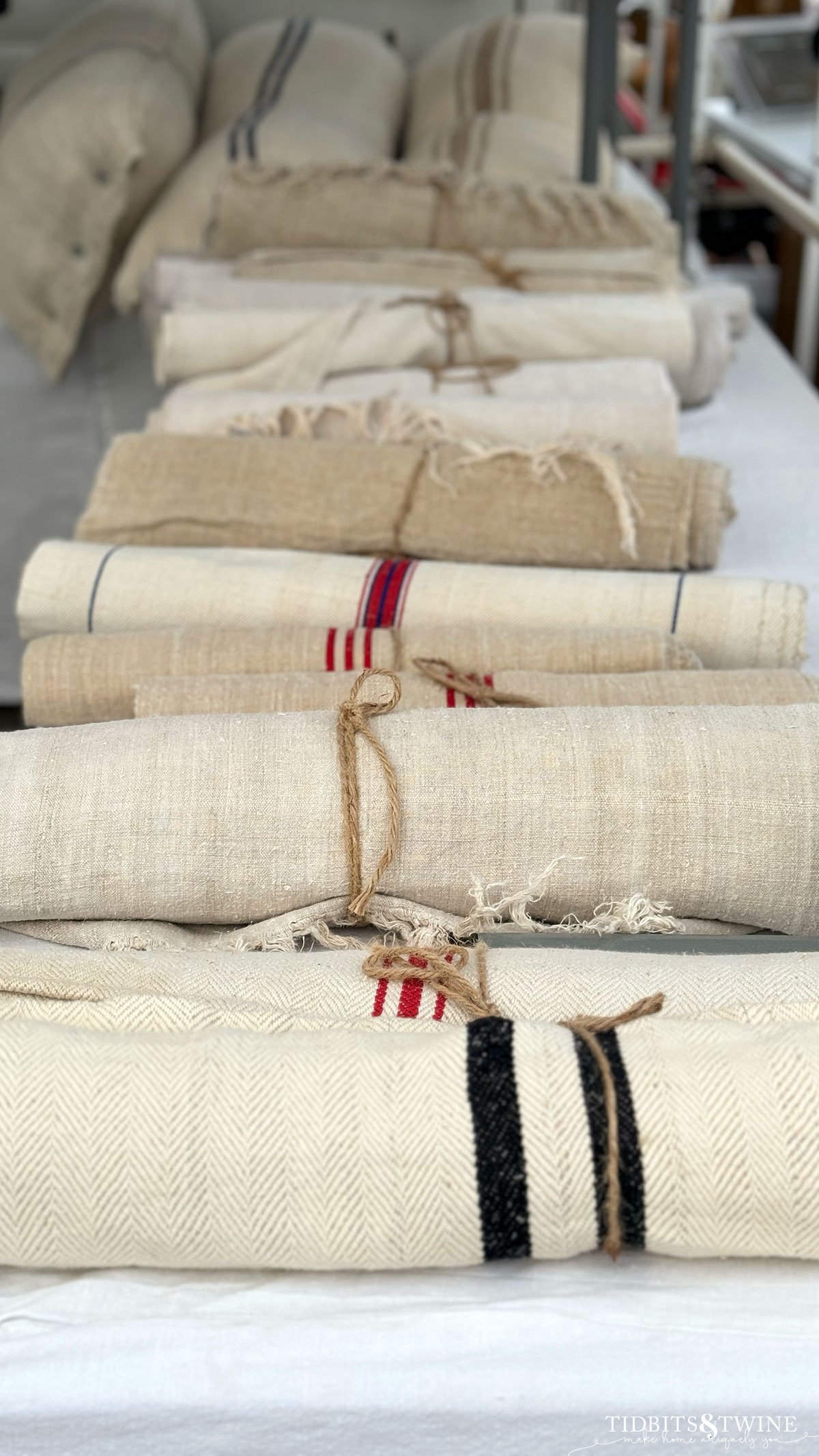 row of antique grain sack table runners rolled up on a table