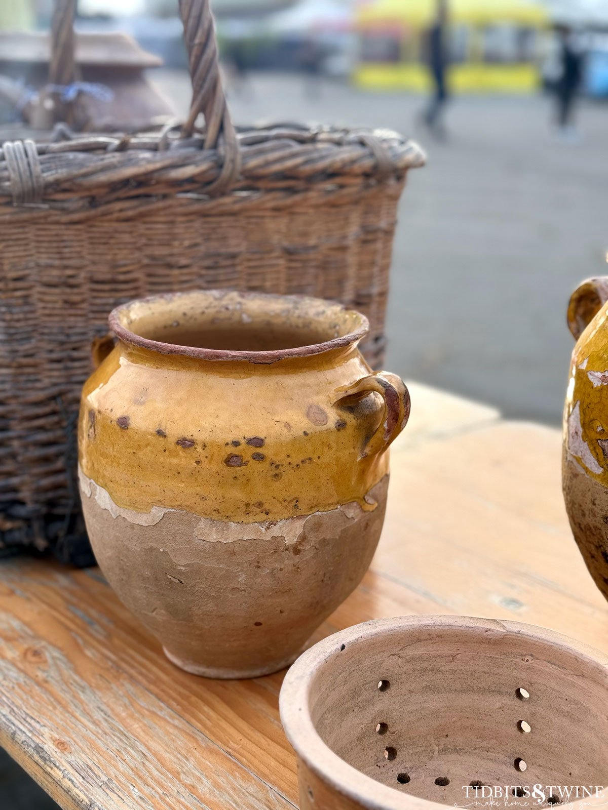 yellow glazed antique french confit jar on a table next to a basket at an antique fair