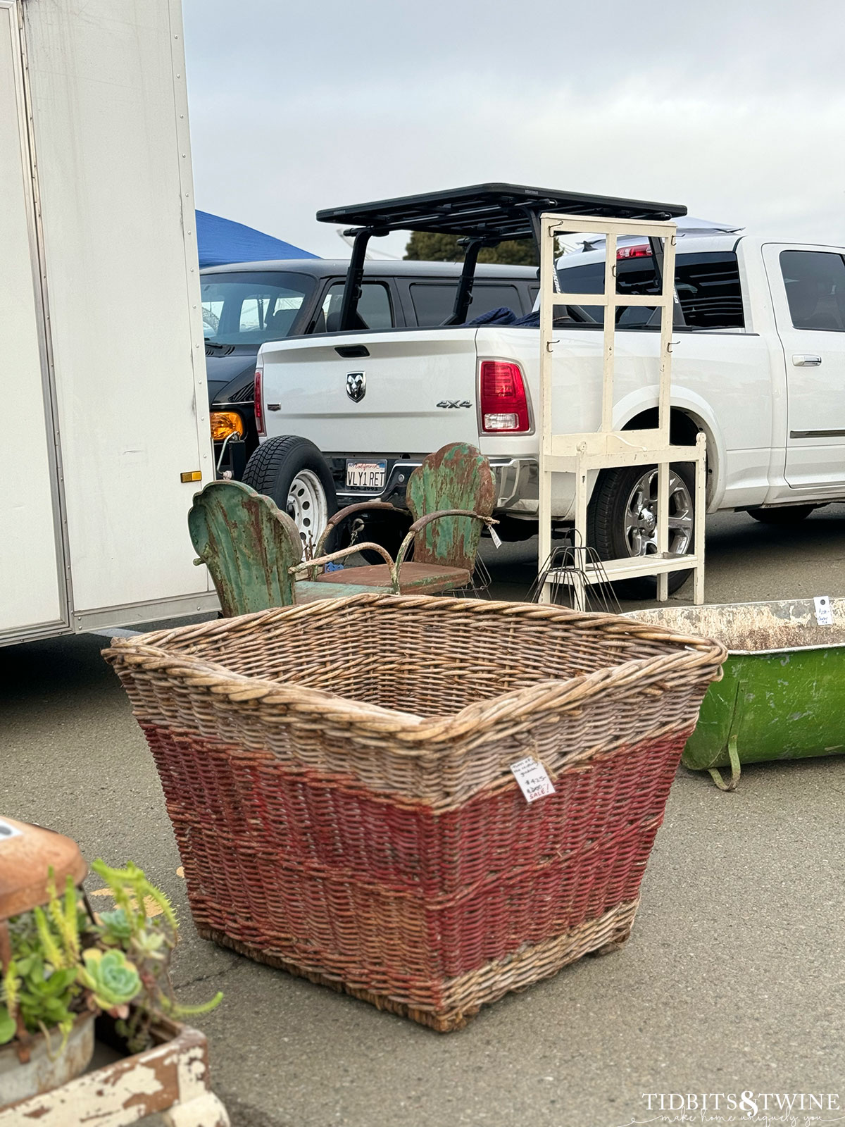 Oversized antique french basket with red painted base sitting in the parking lot at an antique fair