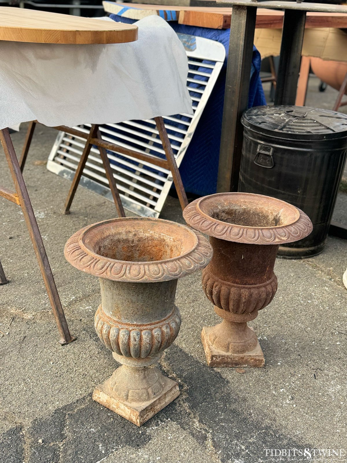 two antique iron urns sitting in a parking lot for sale at an antique fair
