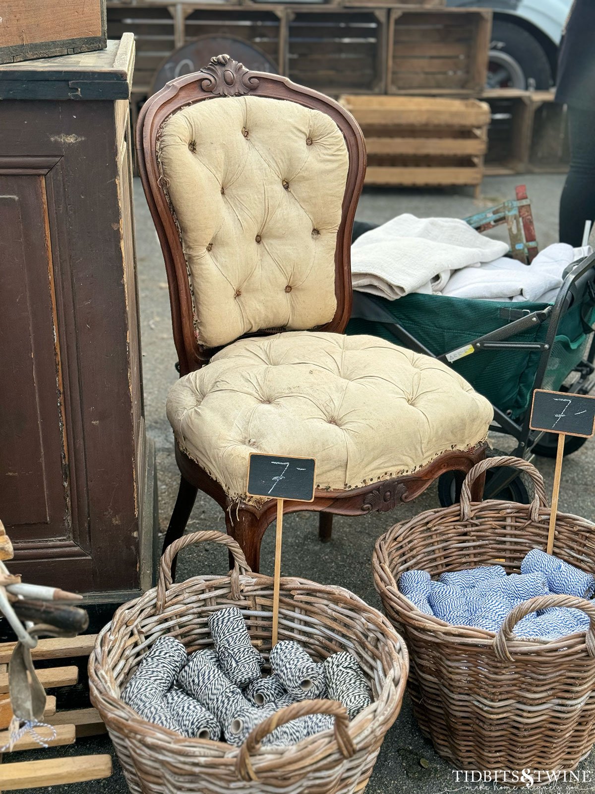 antique yellow tufted chair with baskets at the base holding spools of colored twine at an antique fair