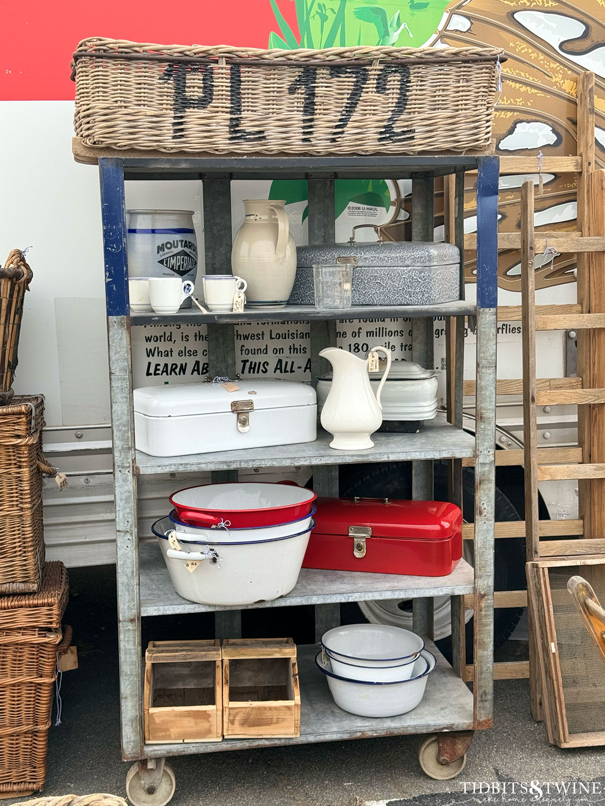 metal rolling shelves holding enamel bowls, ironstone and an oversize basket at an antique fair