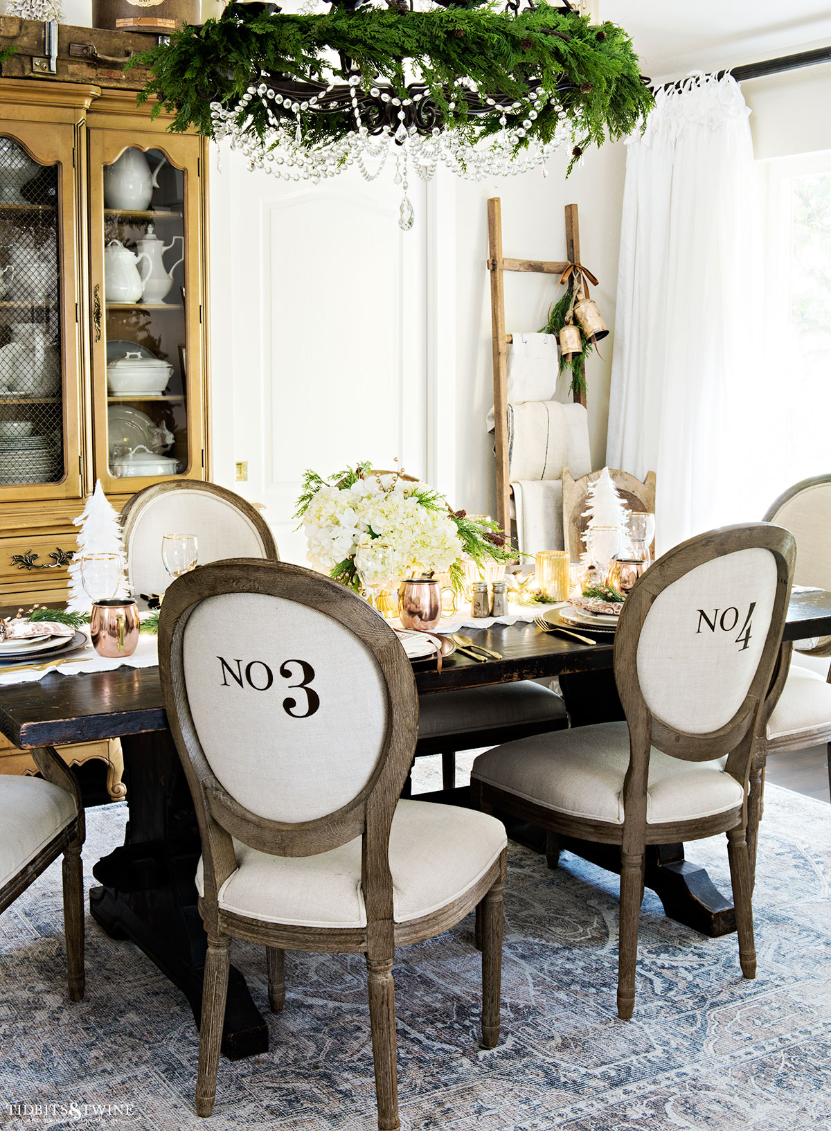 Christmas dining room set for dinner with neutral plates and copper accents and white flowers