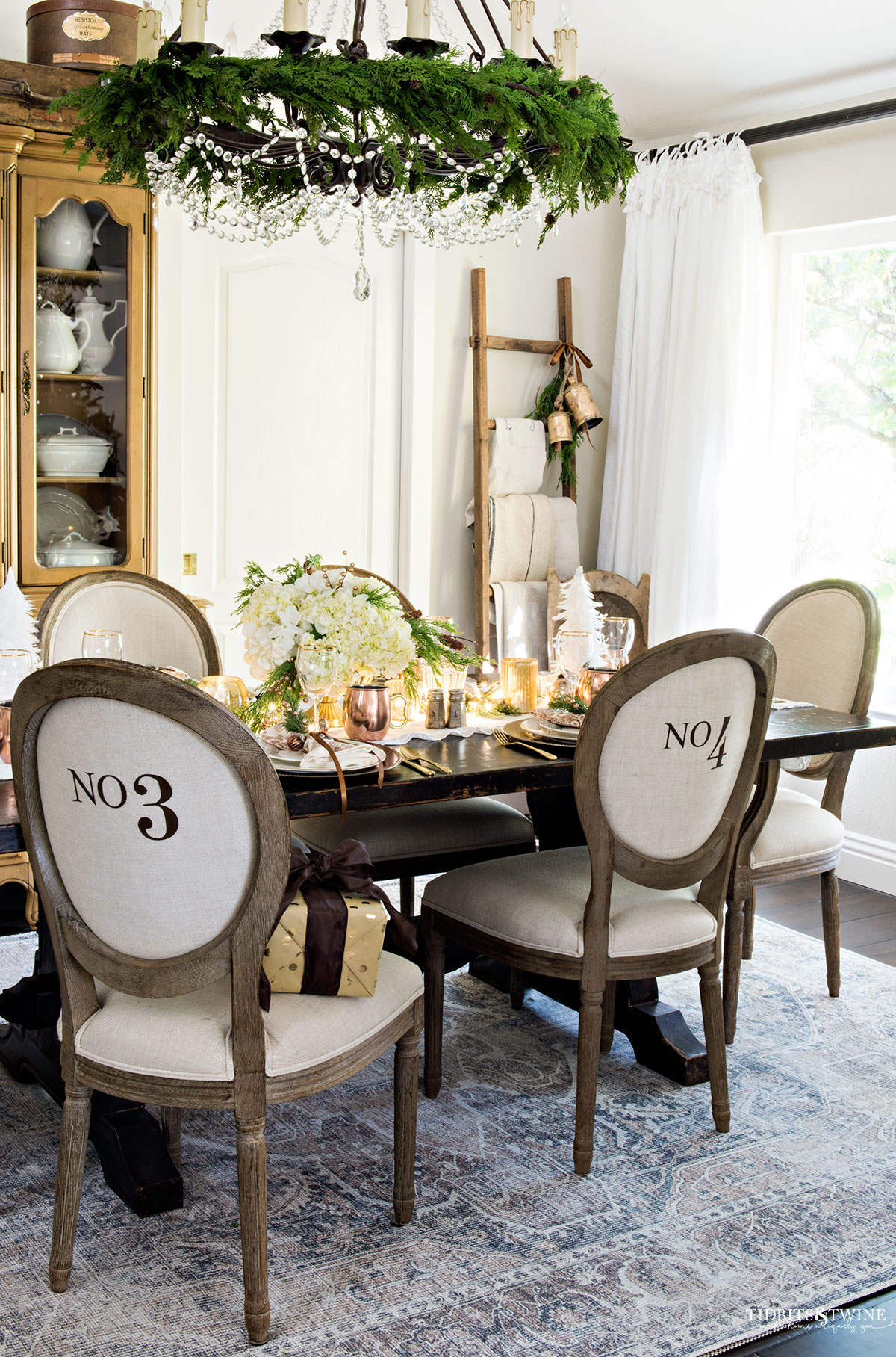 french christmas dining room decorated in neutrals with copper and greenery on the chandelier